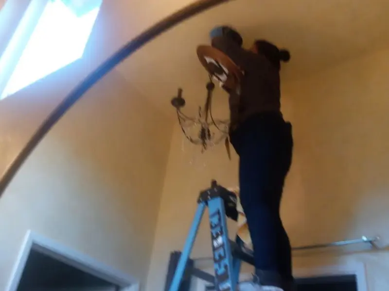Electrician installing a chandelier in a Malvern residence
